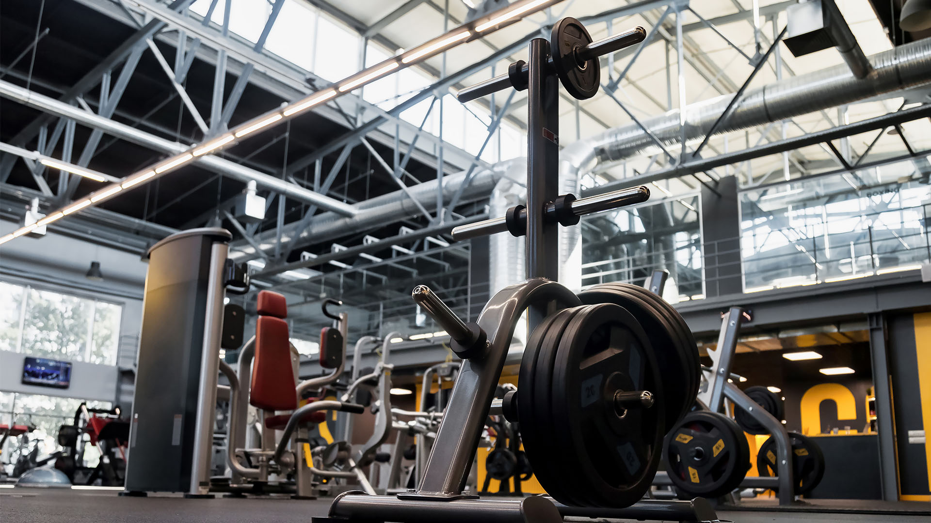 Finding the Perfect Gym: A modern facility with various workout equipment including a squat rack with weight plates, machines, and benches under high ceilings with exposed beams.